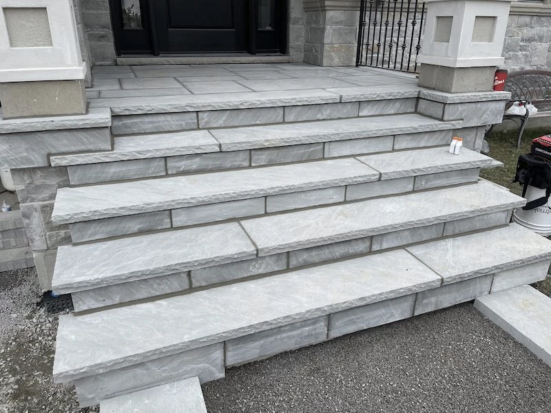 Stone steps leading to a doorway, surrounded by brick walls and construction materials, no identifiable landmarks or historical buildings visible.