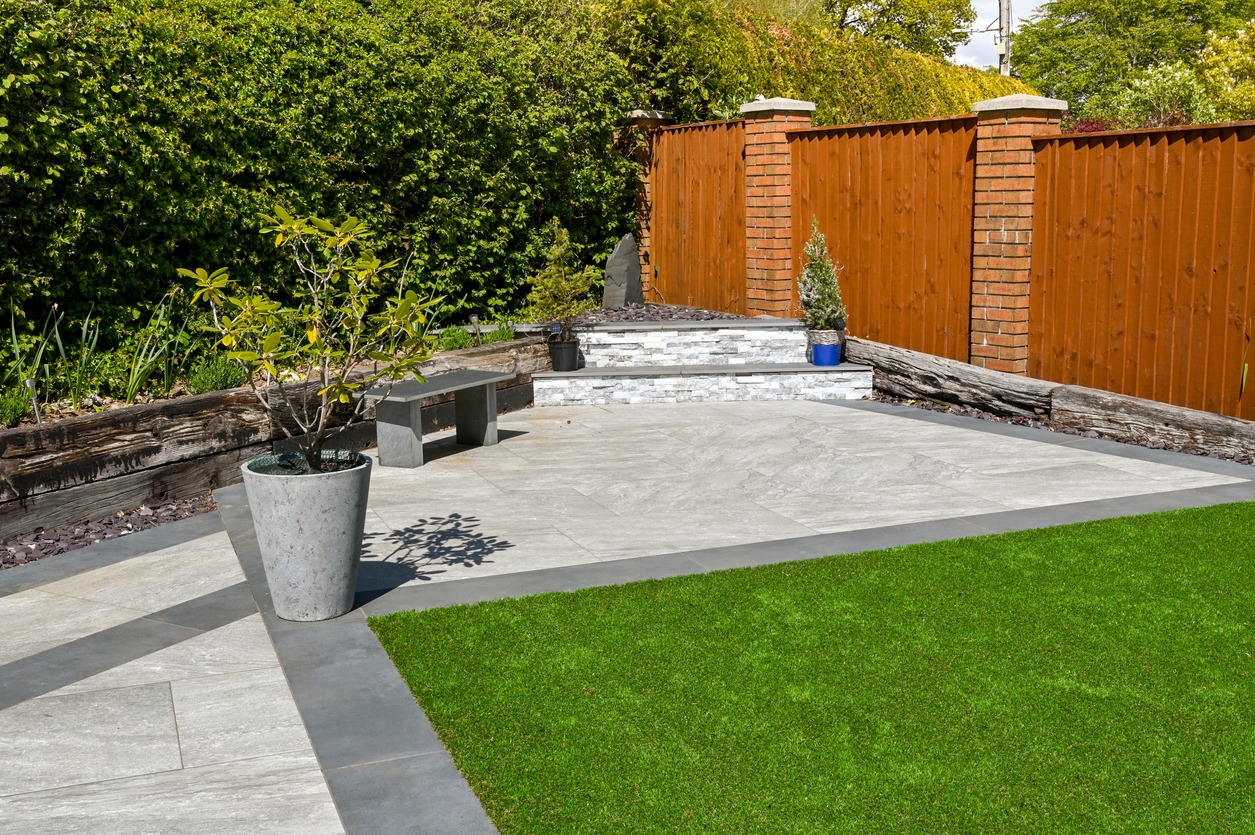 Residential garden landscaped with porcelain paving slabs and artificial grass