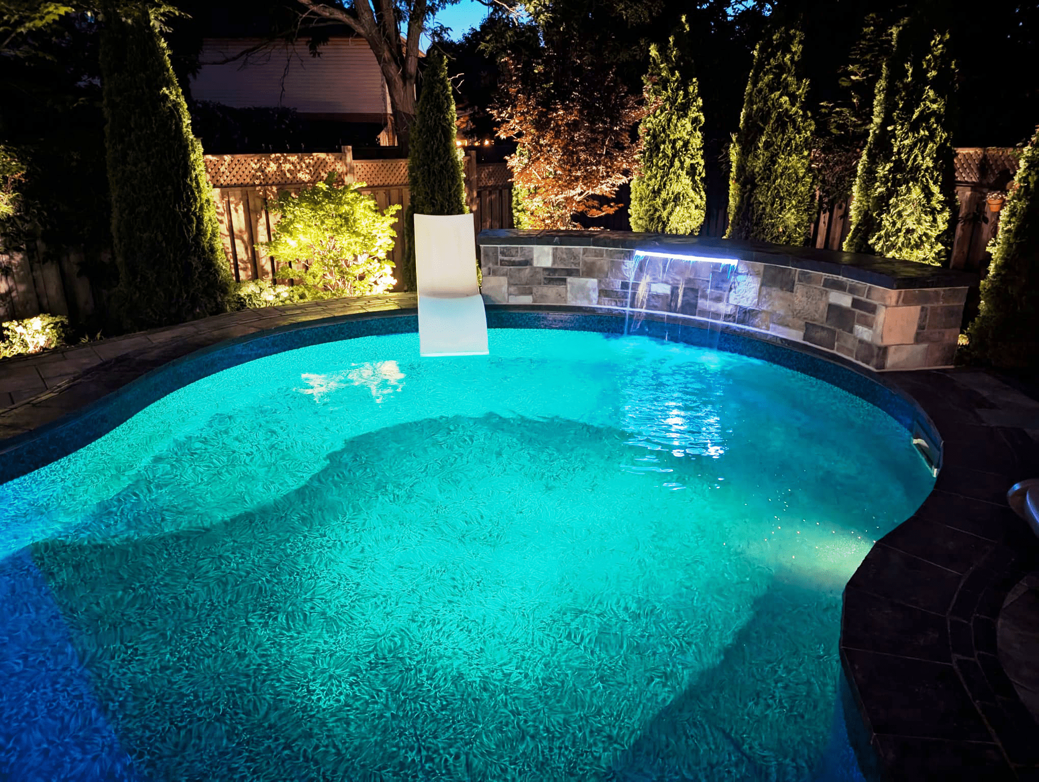 Backyard pool design in the GTA involving a lit pool.
